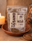 Gran Mitla Sal de Gusano 1kg bag on a clay plate with candle and Oaxacan pottery — handcrafted agave worm salt