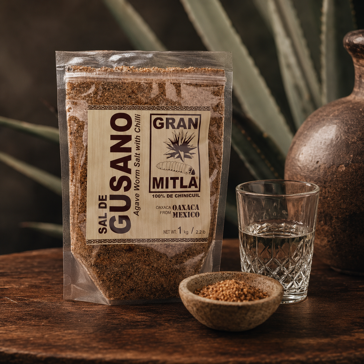 Gran Mitla Sal de Gusano 1kg bag styled with a mezcal glass and agave plant — traditional Oaxacan worm salt for mezcal

