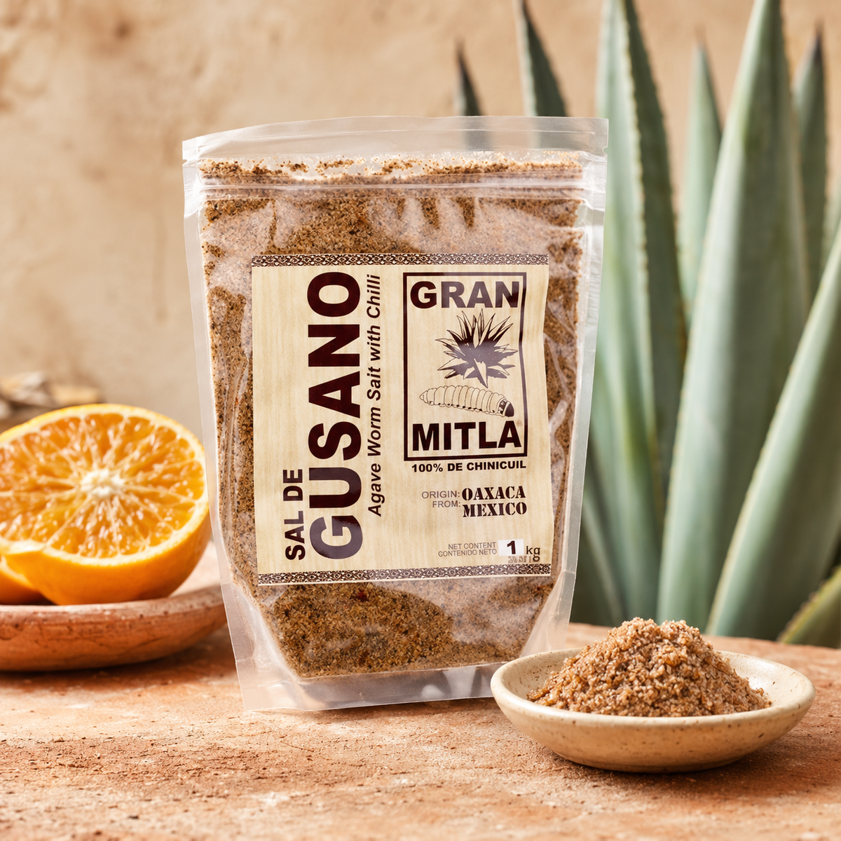 A clear stand-up pouch of Gran Mitla Sal de Gusano (Agave Worm Salt with Chili) is displayed on a rustic wooden surface. The packaging features a cream-colored label with black text and graphics.