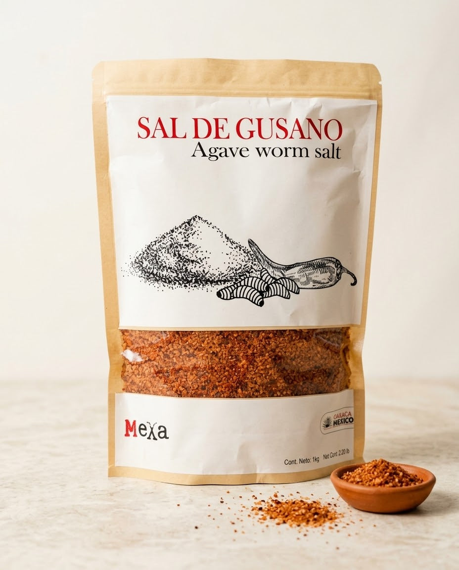 A stand-up pouch of Mexa Sal de Gusano (Agave Worm Salt) on a light beige background, with a small wooden bowl and scattered seasoning in front.